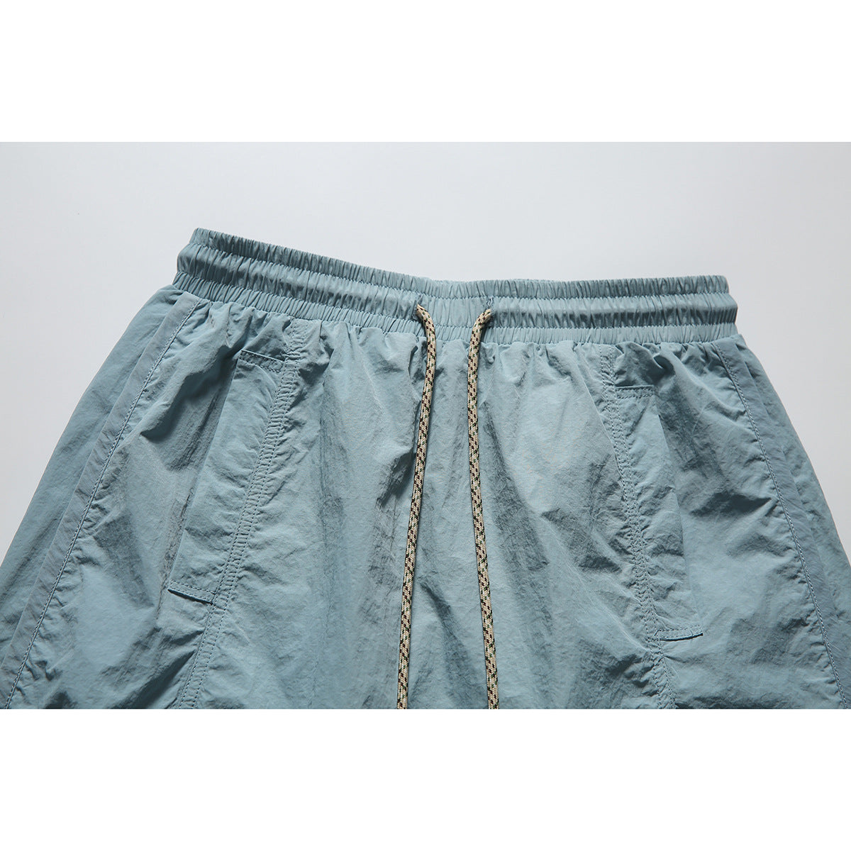 Close-up of a blue-gray skirt's elastic waistband, patterned drawcord, and front pockets.
