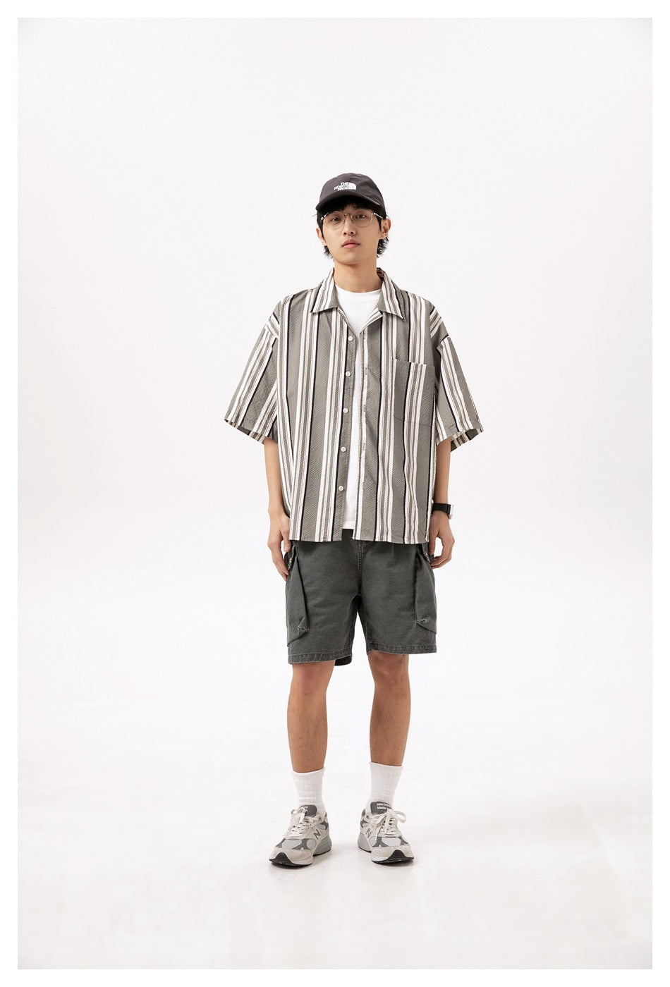Front view of a person in washed gray cargo shorts, a striped short-sleeve shirt, white tee and gray sneakers