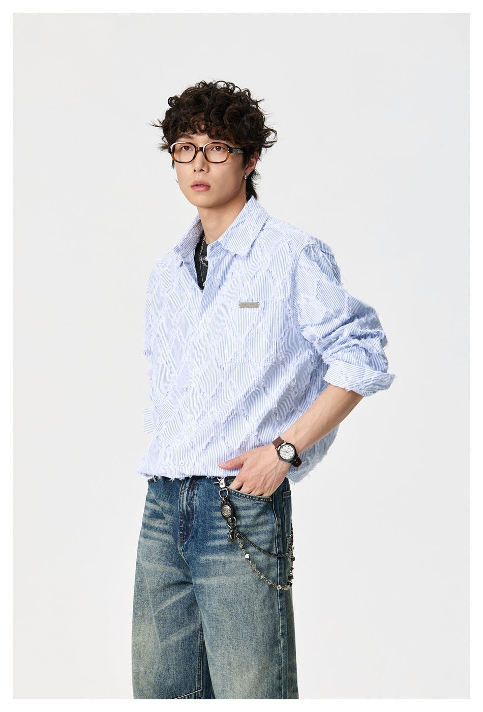 Model wearing a light blue pinstriped shirt with distressed diamond details, layered over a dark tee.