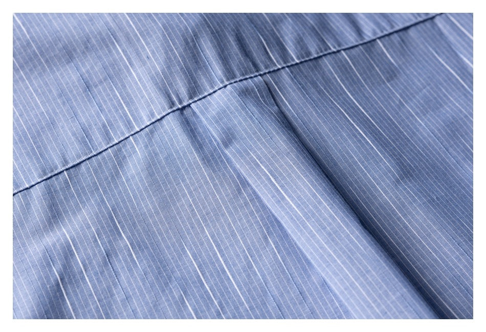 Close-up of a stitched seam on blue fabric with fine white pinstripes.