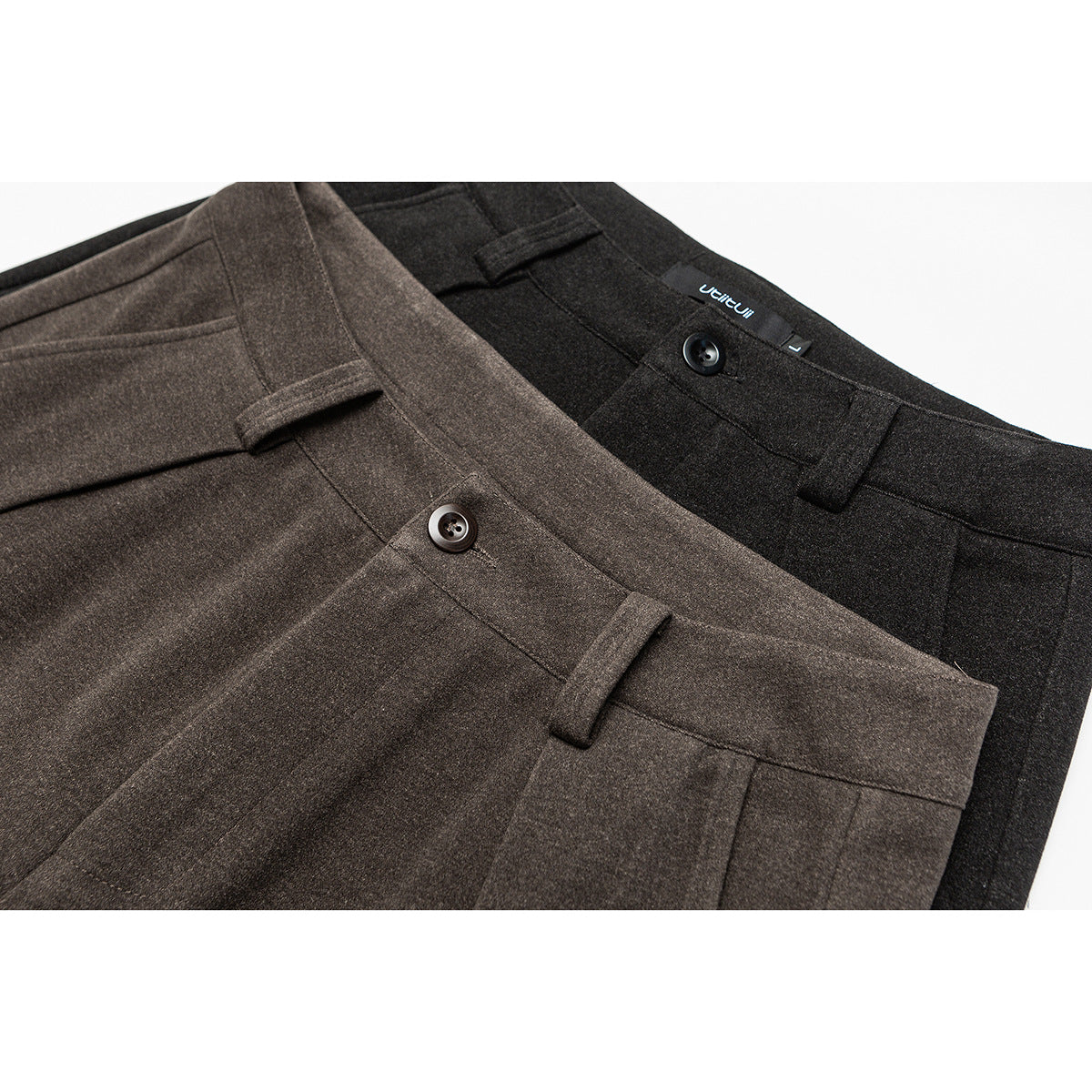 Close-up of brown and charcoal trousers showing waistbands, buttons, belt loops and seams.