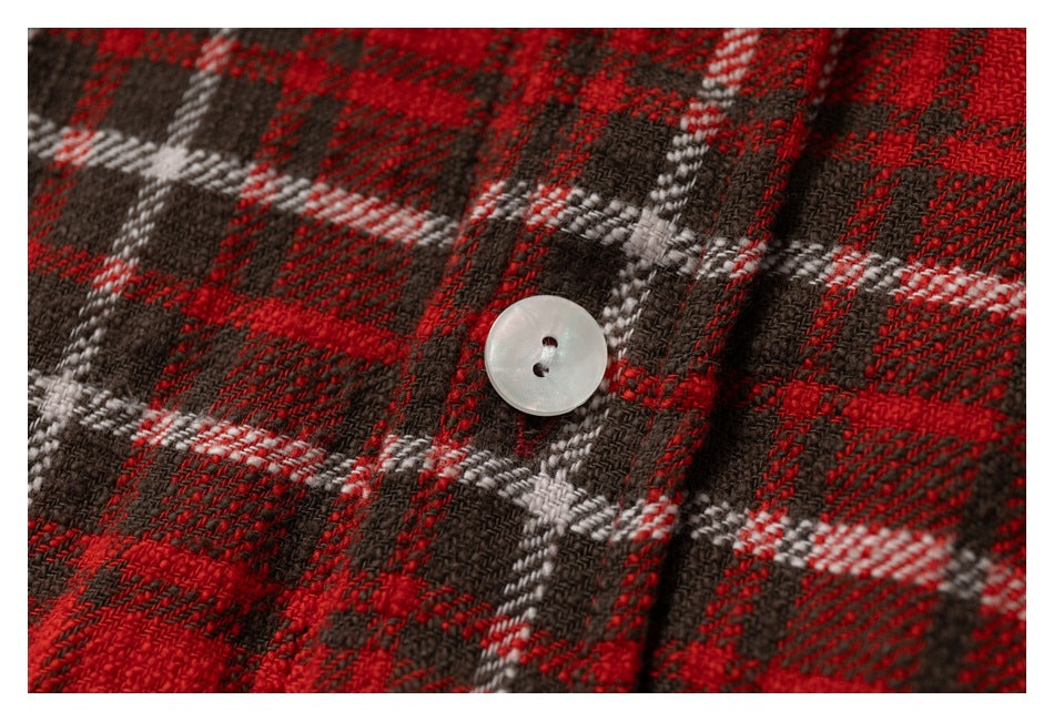 Close-up showing a white button and woven red, black, and white plaid fabric.