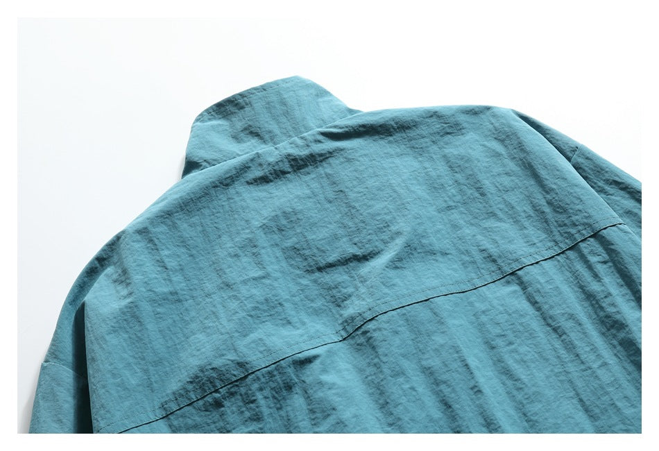 Close view of the teal jacket's upper back, collar, and curved shoulder seam.