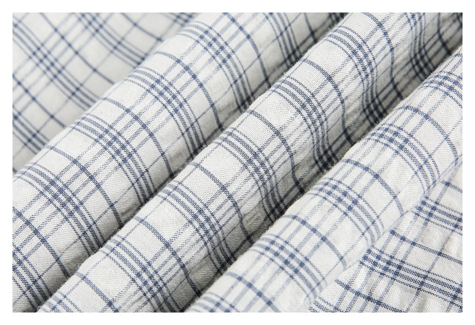 Close-up of folded cream plaid fabric showing its blue-gray checks and woven texture.