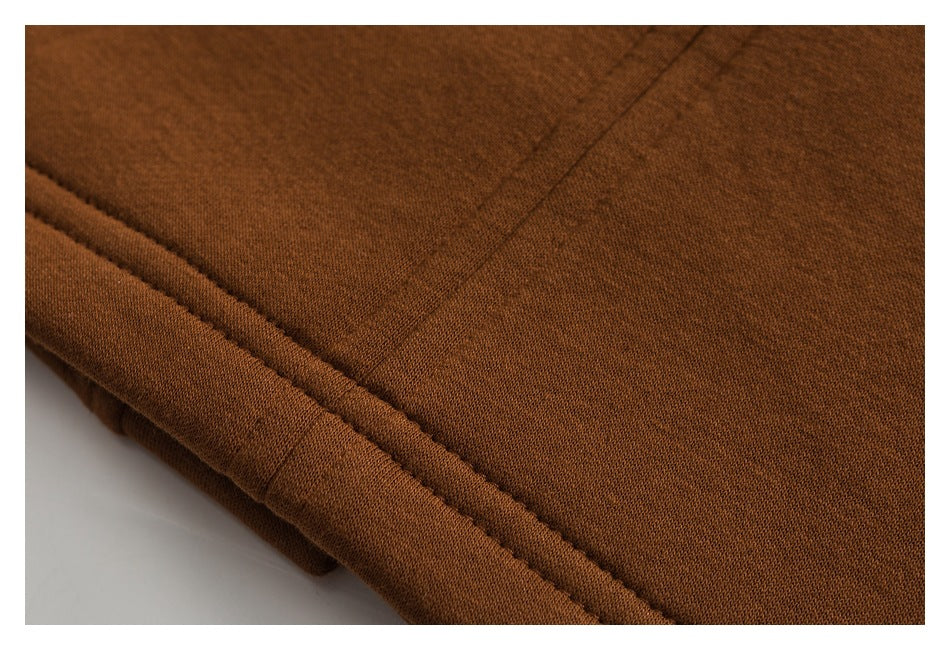 Close-up of brown fabric showing a folded edge and parallel stitching.