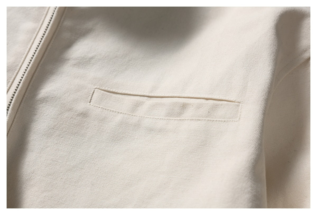 Close-up of a narrow welt pocket on the ivory jacket, with part of the zipper visible.