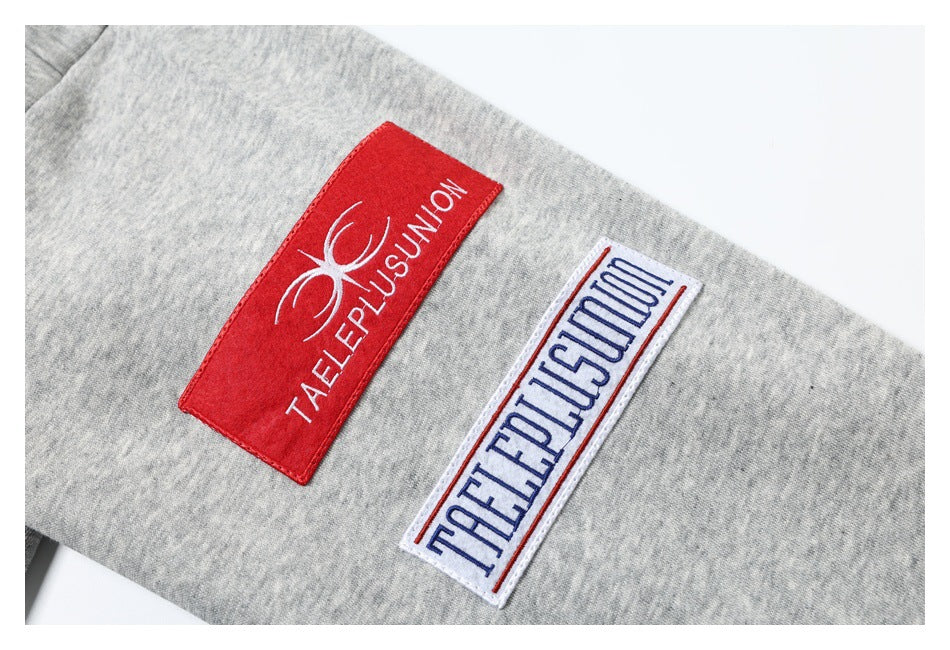 Close-up of two embroidered text patches on gray heathered fabric.