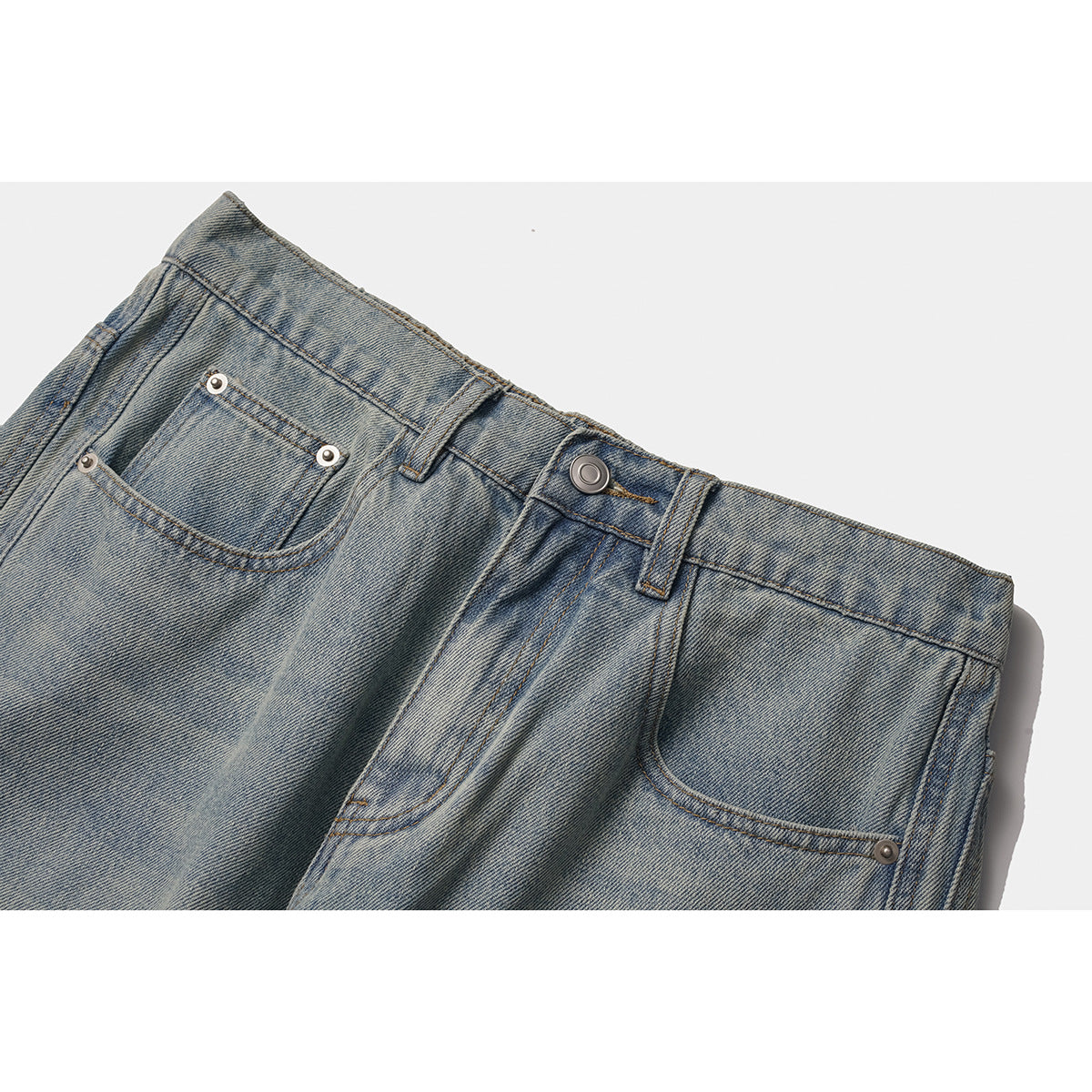 Close-up of light-wash jeans showing the waistband, button, belt loops, front pockets and rivets.