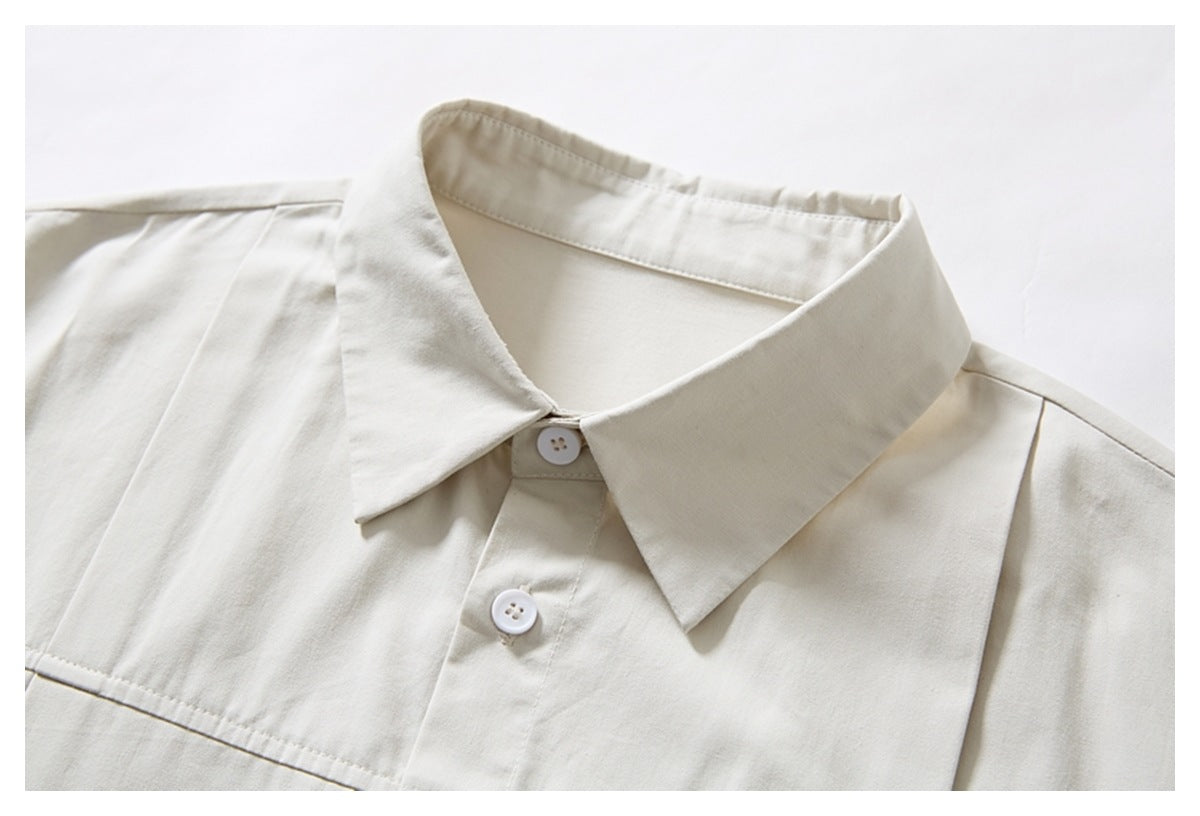 Close-up of an ivory shirt's pointed collar, white buttons, and upper front seams.