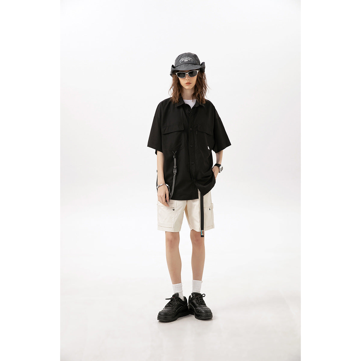 Model wearing an oversized black short-sleeve button-up shirt with chest pockets and off-white cargo shorts.