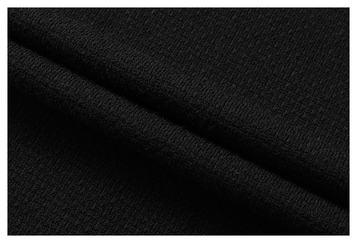 Close-up of black fabric with a fine, textured knit surface and a diagonal fold.