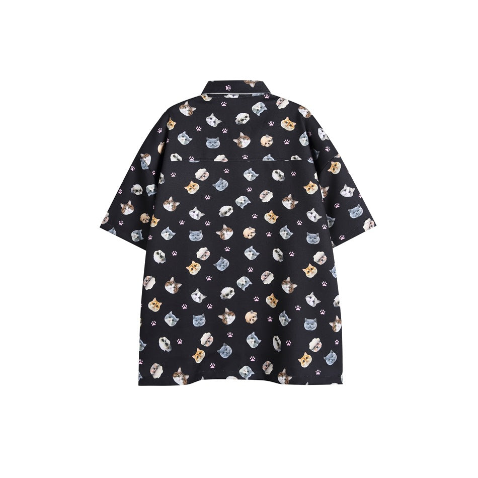 Back view of a black oversized short-sleeve shirt covered in cat faces and pink paw prints.