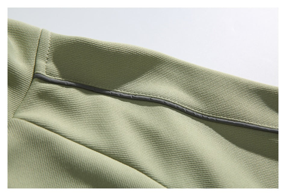 Close-up of a dark piping seam running across the textured sage-green jacket fabric.