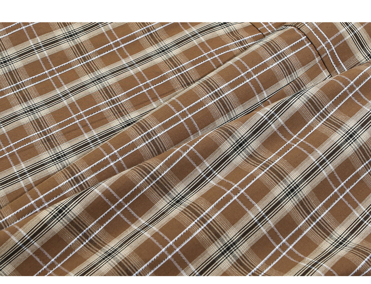 Close-up of brown plaid fabric with intersecting cream, white, and black lines.