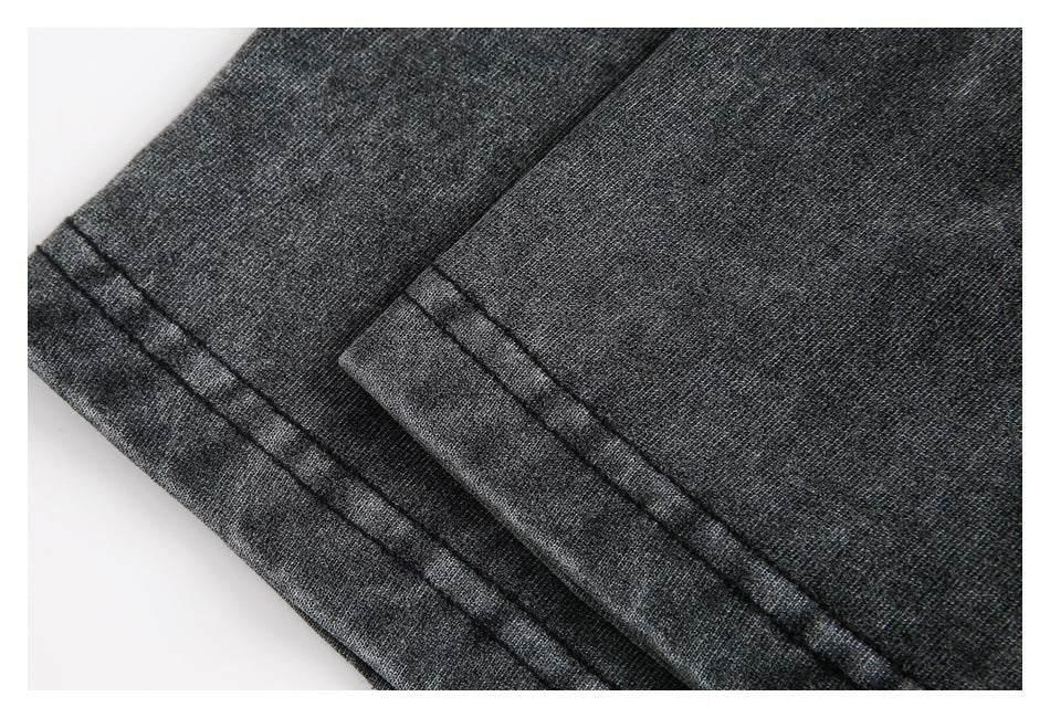 Close-up of two stitched hems on charcoal garment fabric.