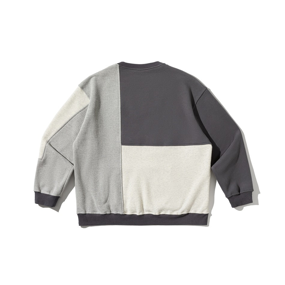 Flat lay of a color-block sweatshirt back in charcoal, gray, and cream, with matching dark ribbed cuffs and hem.