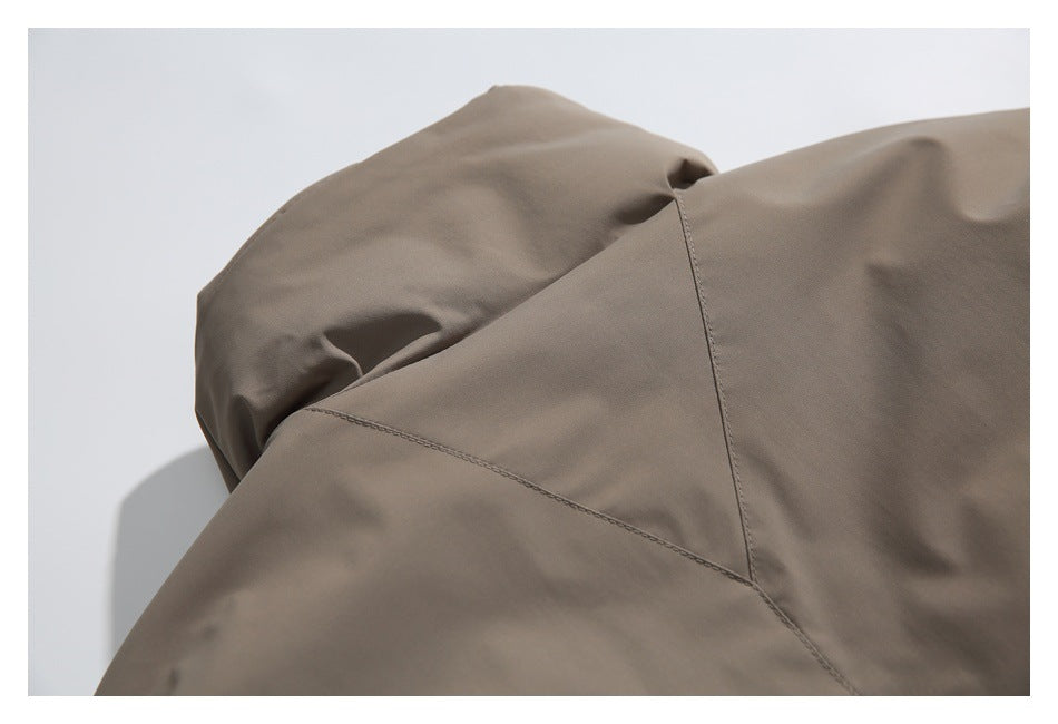 Close-up of taupe garment construction showing intersecting seams at a curved panel junction.