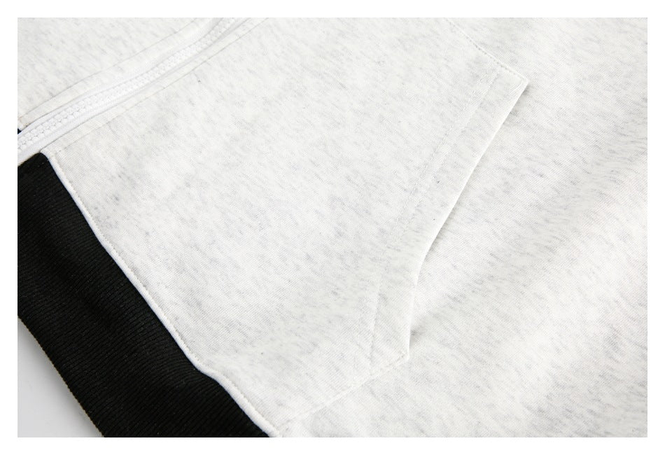 Close-up of the pocket seam and black ribbed hem on a heather-gray sweatshirt.