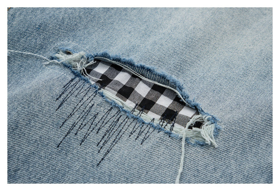 Close-up of a frayed denim tear revealing black-and-white checked fabric beneath.