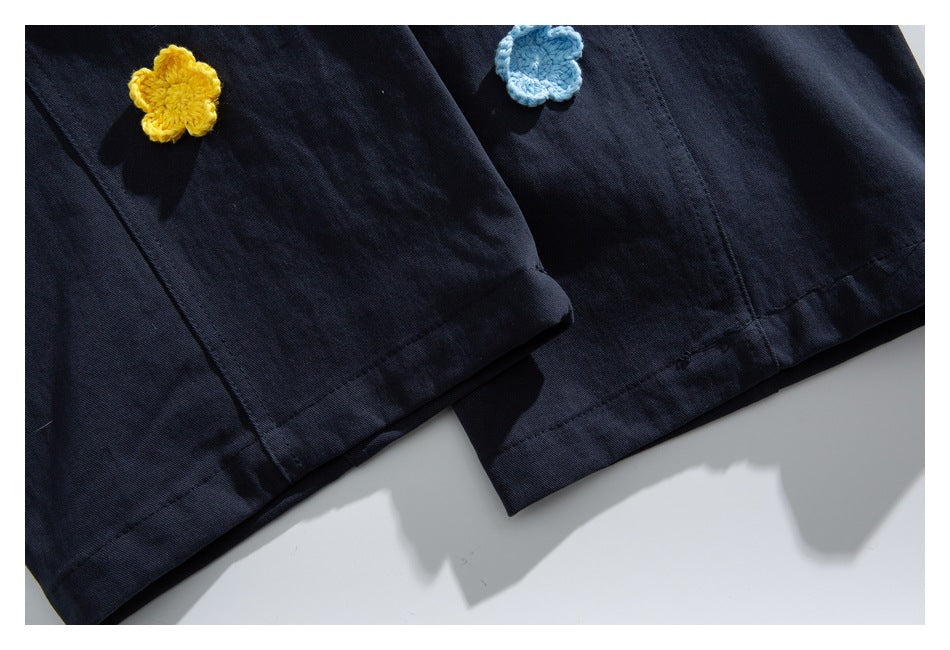 Close-up of dark navy garment hems with small yellow and light blue flower appliqués.