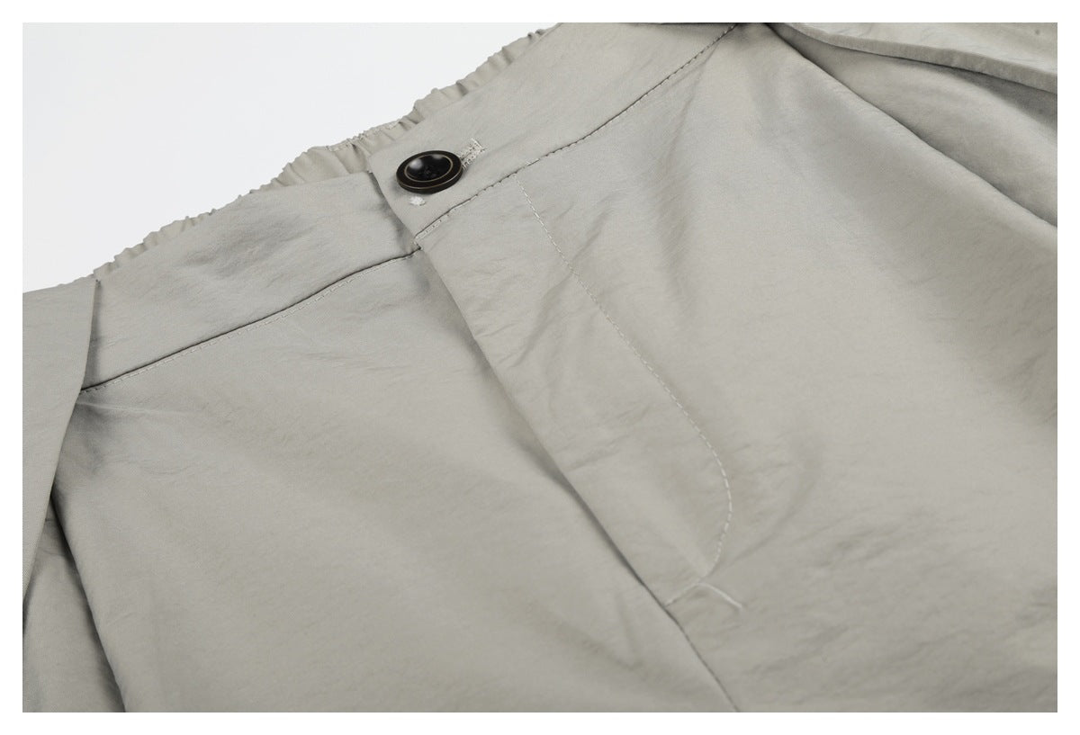 Closer view of light gray shorts with a dark waist button, fly stitching, and front pleat.