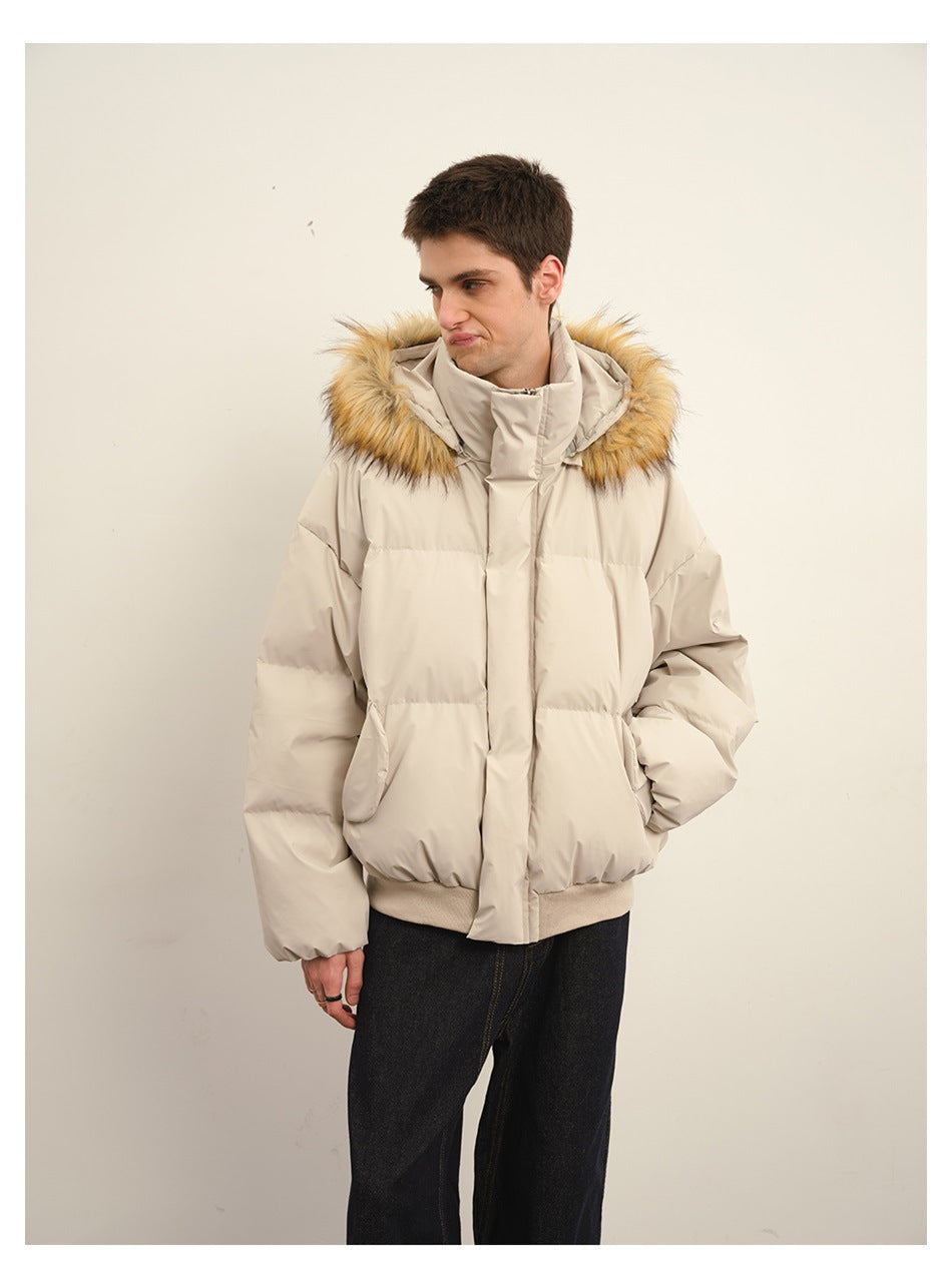 Man wearing a beige puffer jacket with fur-trimmed hood, one hand in the pocket, dark jeans, front view
