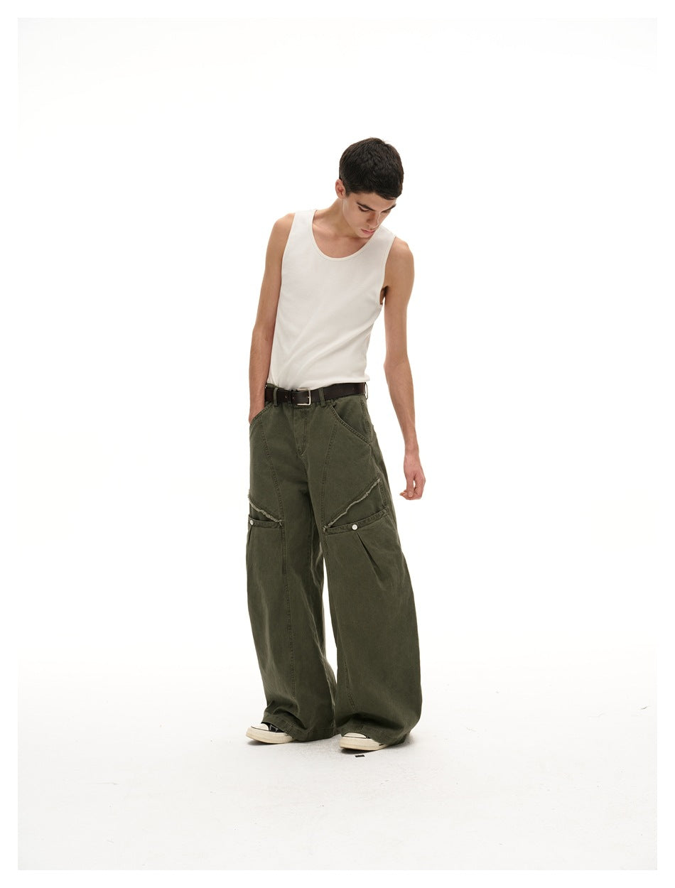 Model wearing dark olive wide-leg pants with layered knee panels and a white tank top, angled front view.