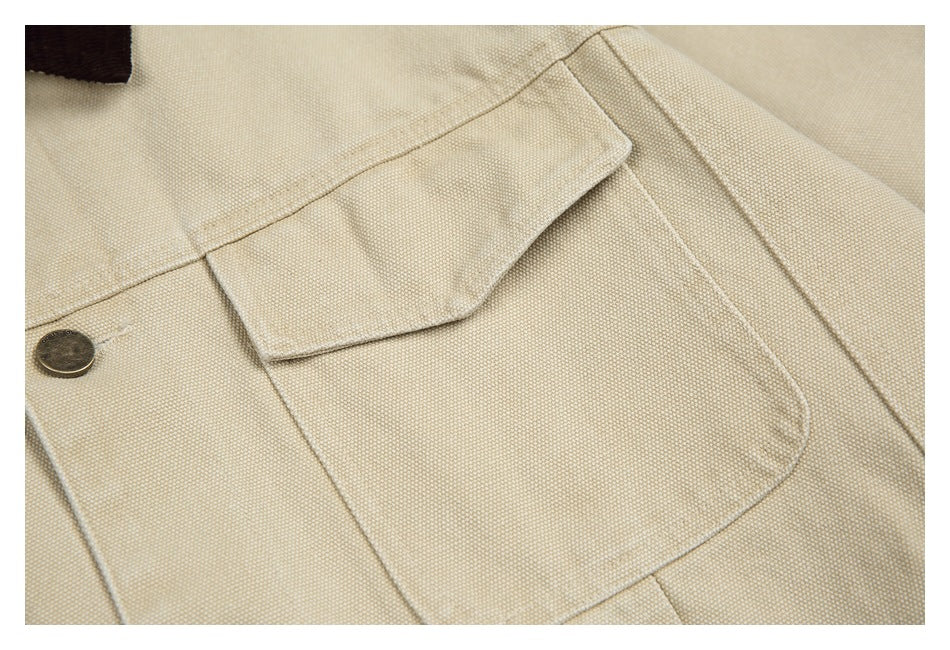Close-up of a beige jacket's flap chest pocket, textured fabric, stitching, and a metal button.