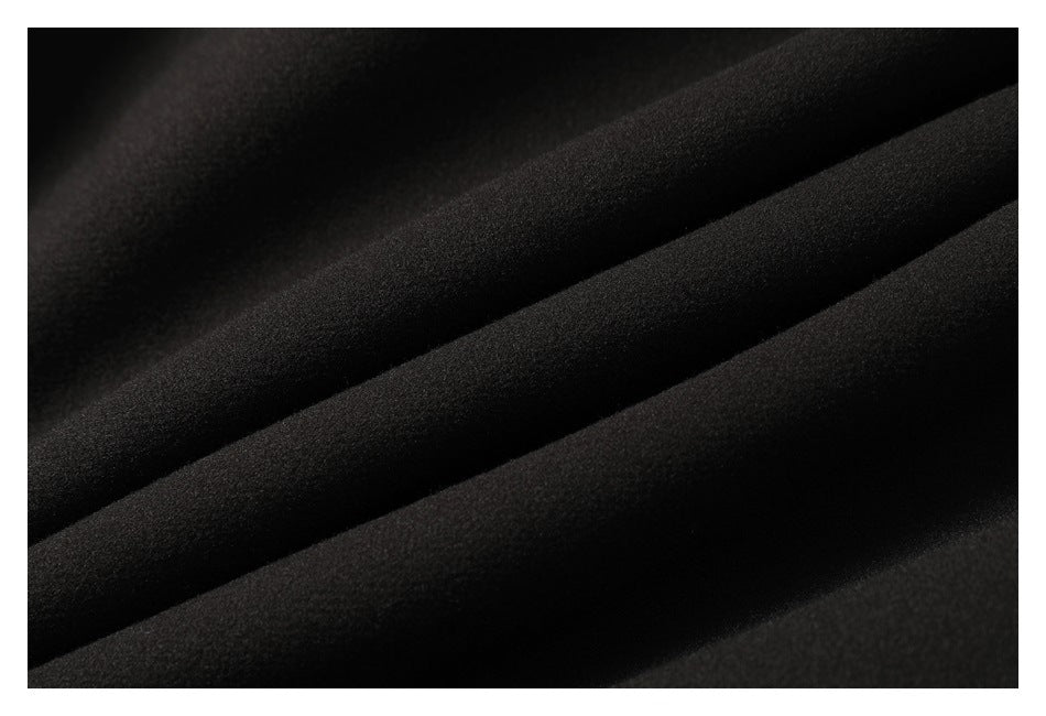 Close-up of black fabric arranged in overlapping diagonal folds.