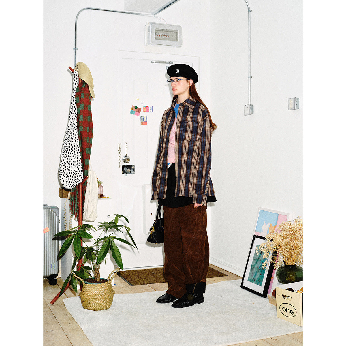Model wearing an oversized blue, brown and beige plaid button-up shirt with a chest pocket and brown wide-leg pants.