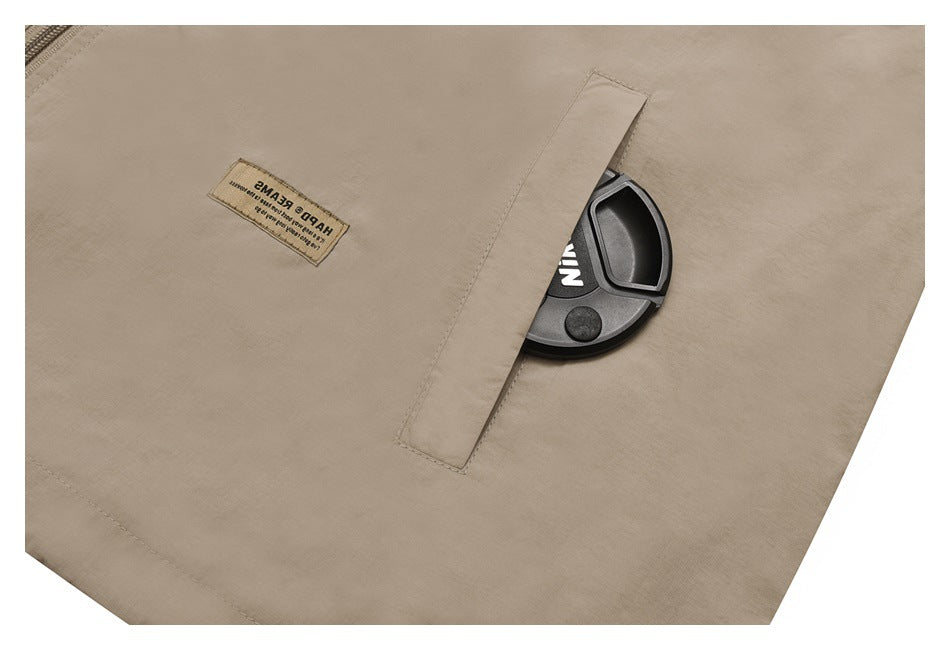 Close-up of a beige jacket pocket with a flap, sewn text label, and a black item partly visible.