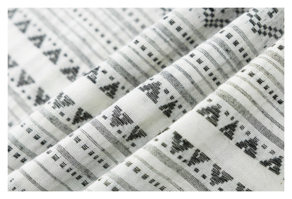 Macro view of white shirt fabric with black geometric motifs and narrow gray stripes.