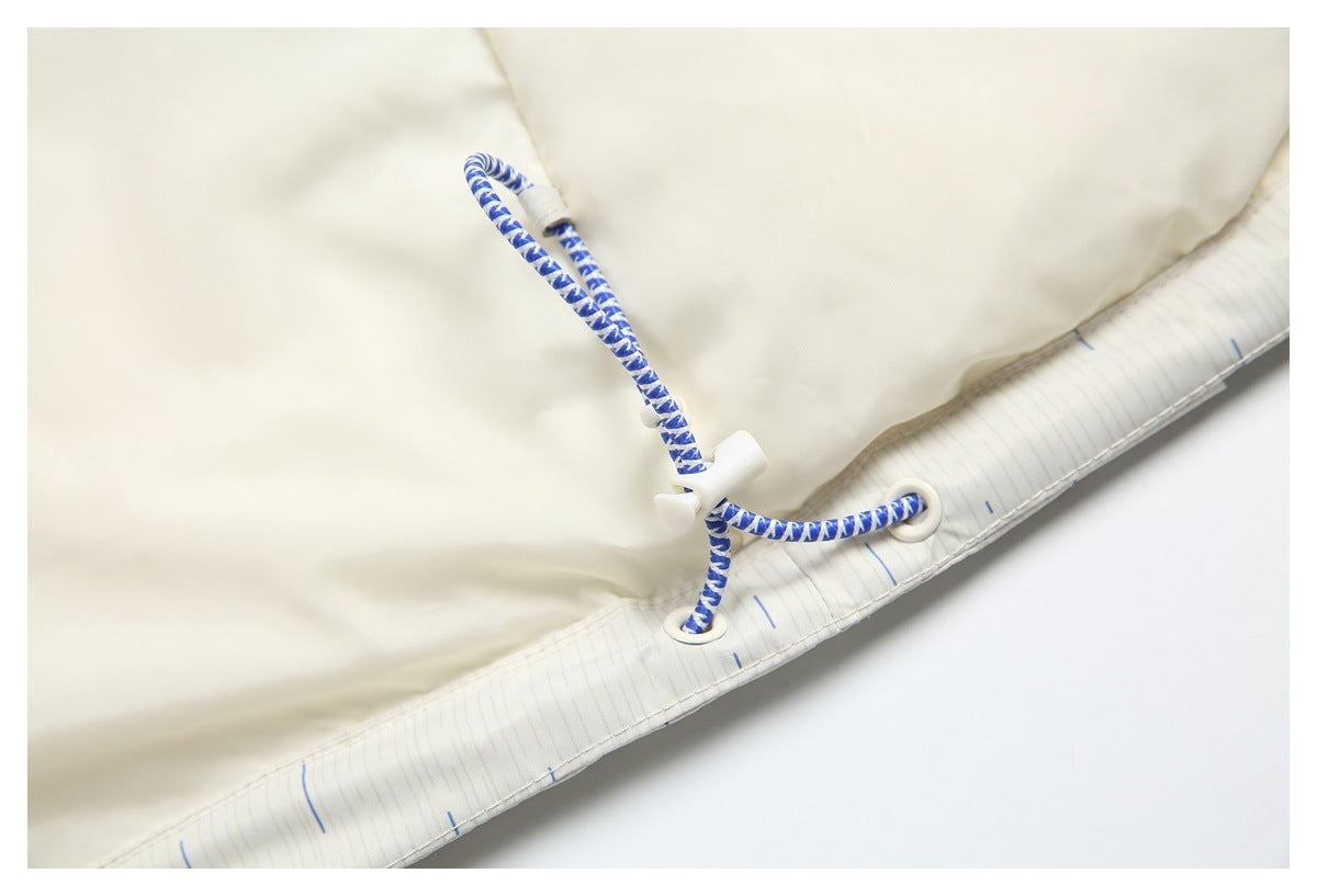 Close-up of a blue-and-white braided drawcord, white adjuster and eyelets along the hem of an off-white garment.