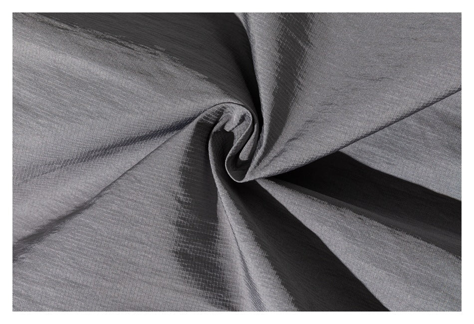 Close-up of gray jacket fabric gathered into folds to show its surface texture.