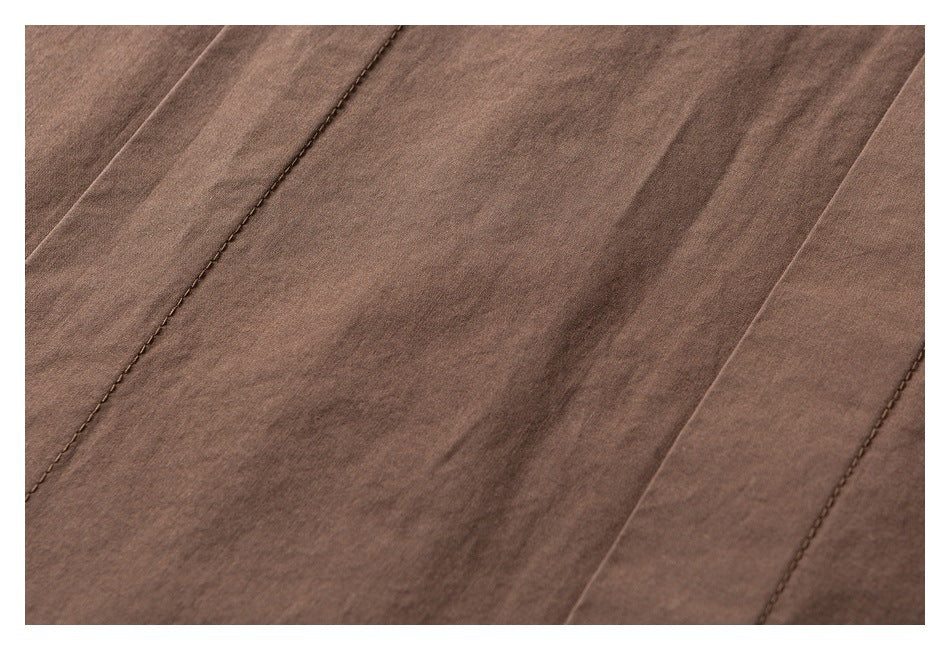 Close-up of brown garment fabric with parallel panels and visible topstitched seams.