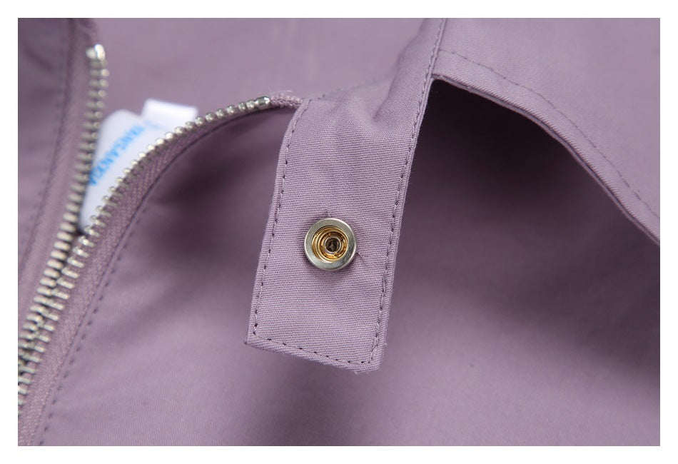 Close-up of a metal snap on a mauve inner flap beside the open zipper.