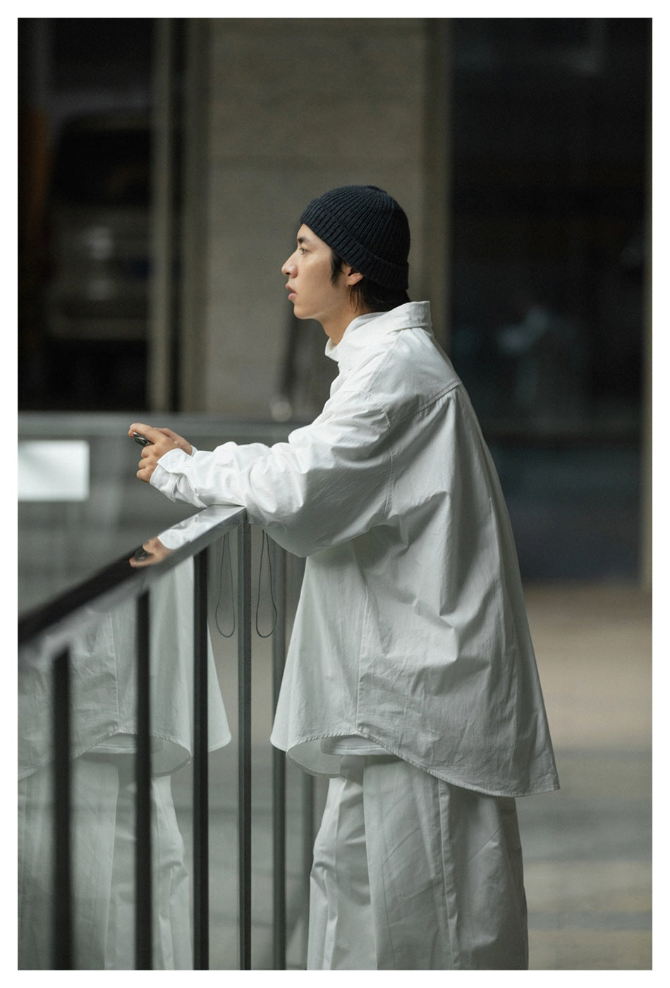 Side and back view of a model wearing an oversized white shirt and matching trousers with a black beanie.