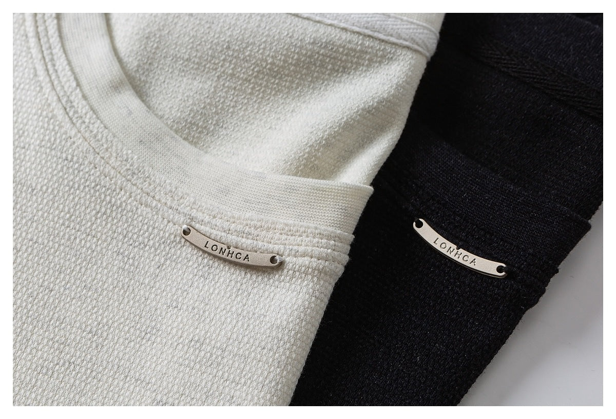Close-up of ivory and black textured tops, each with a small curved metal LONHCA plaque.