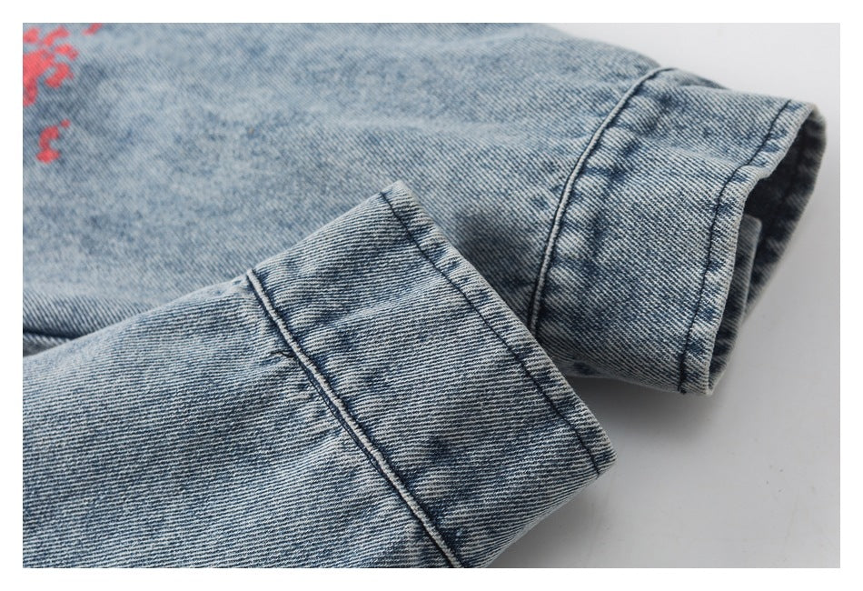 Close-up of two folded blue denim cuffs with visible stitching and a small glimpse of red print.