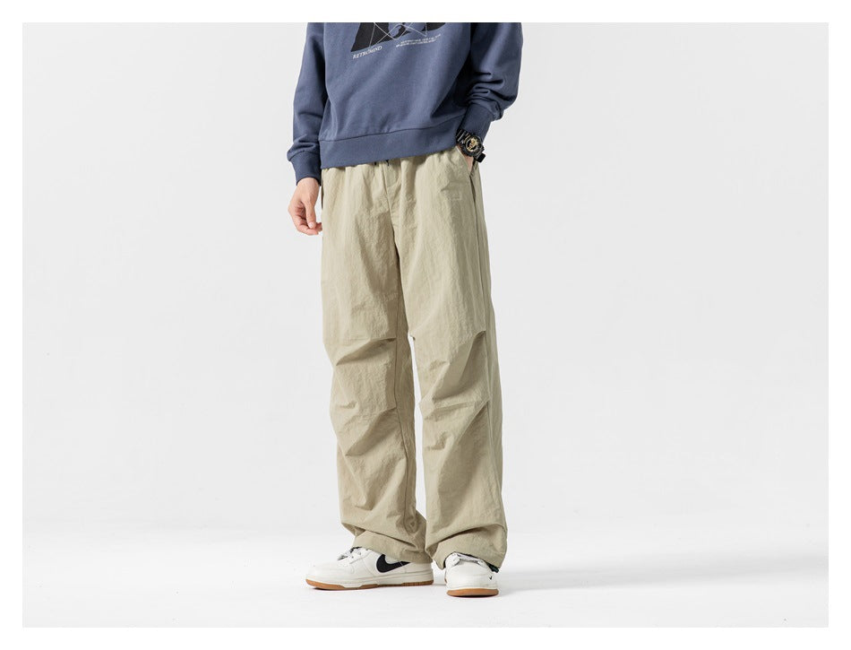 Model wearing khaki wide-leg pants with a blue sweatshirt and white sneakers, front view from the torso down