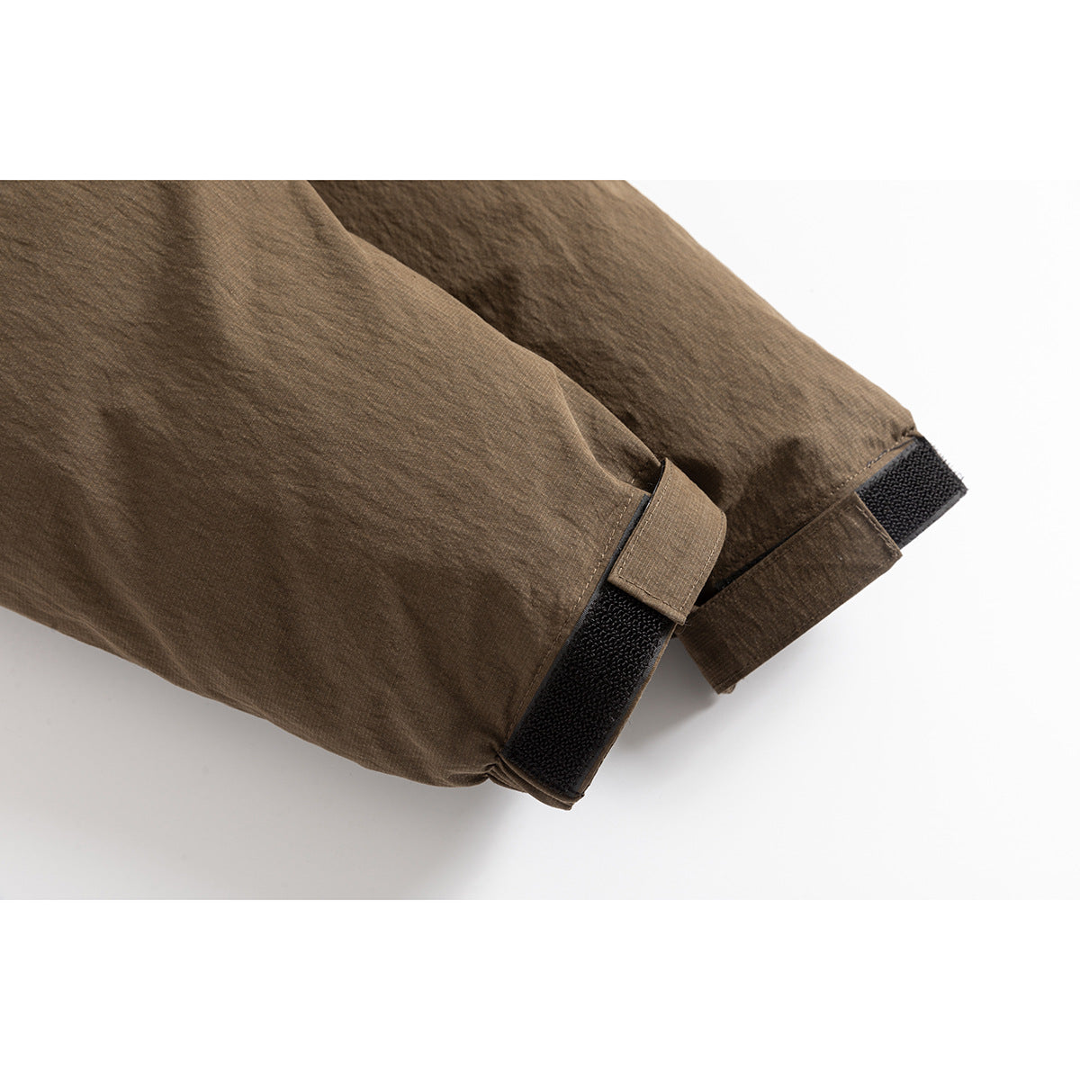 Close-up of a brown jacket sleeve cuff with an adjustable black hook-and-loop tab.