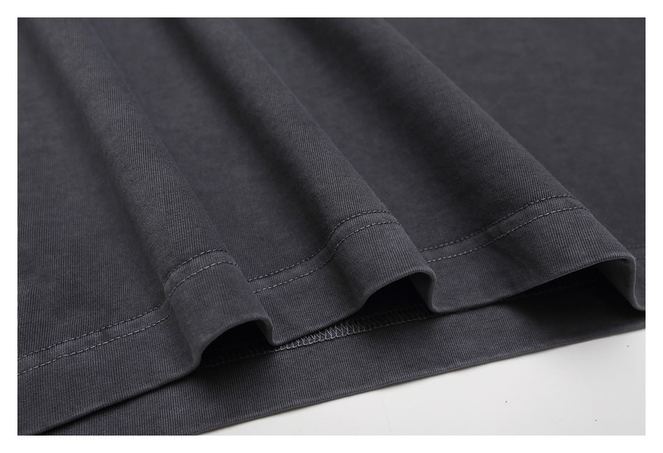 Close-up of the charcoal T-shirt's double-stitched bottom hem and inner overlock stitching.