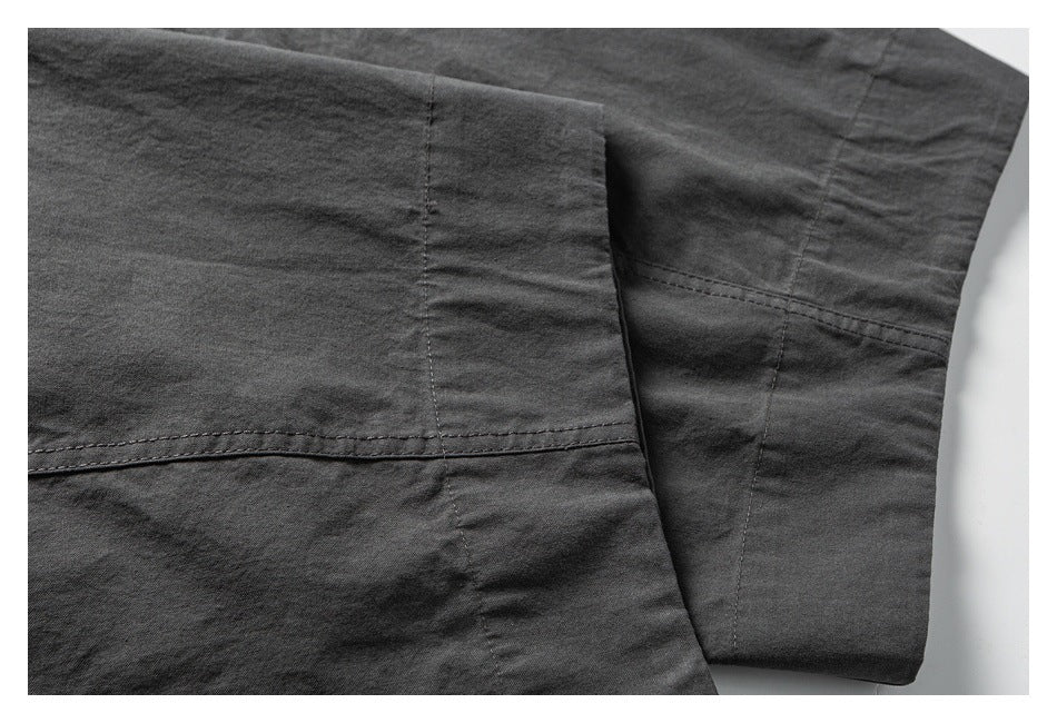 Close-up of charcoal pants showing the leg panel seams and stitched hem.