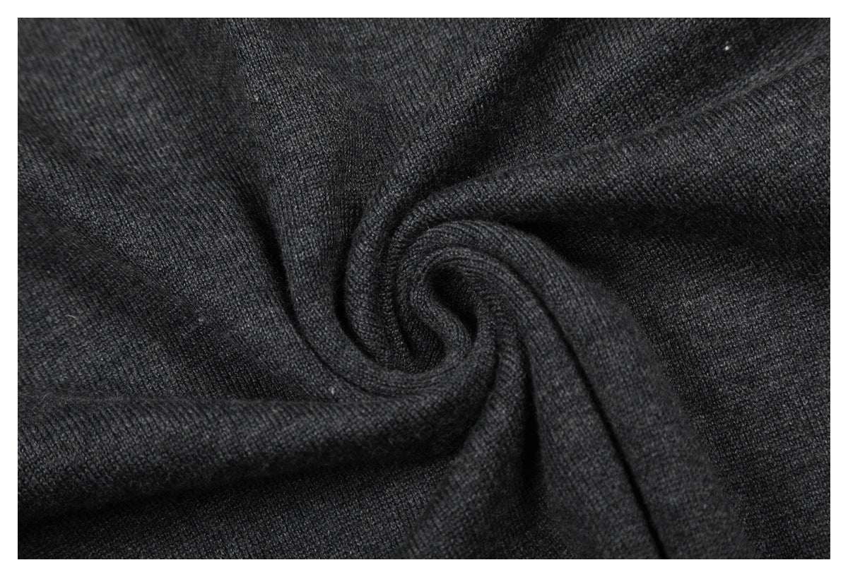 Close-up of dark charcoal gray knit fabric gathered into a swirl, showing its fine texture.