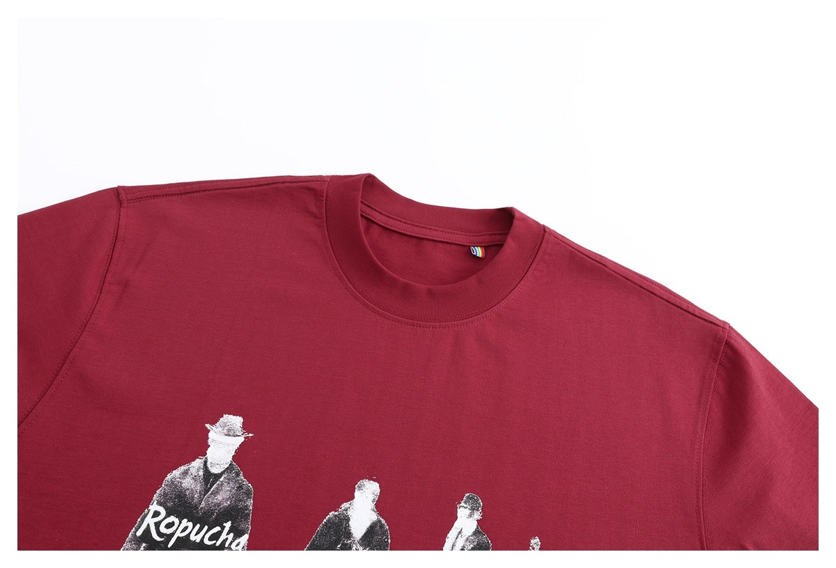 Cropped close-up of a burgundy crew-neck T-shirt with part of its monochrome figure print visible.