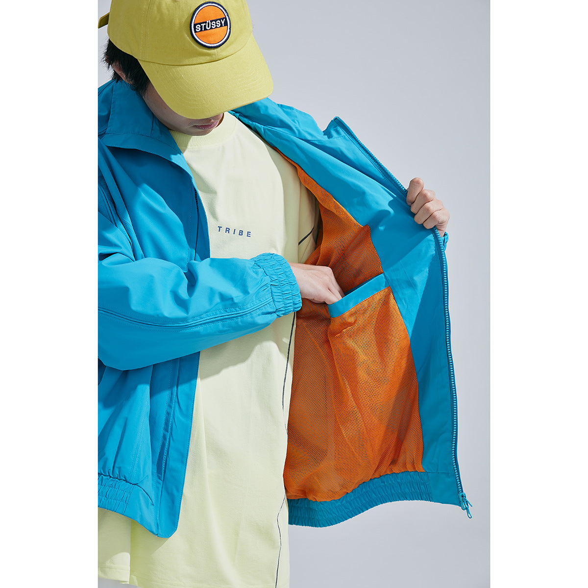 Close view of a turquoise jacket opened to show its bright orange mesh lining and interior pocket.