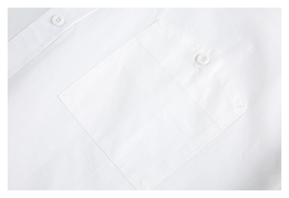 Close-up of a white shirt's square chest pocket with a buttoned flap.