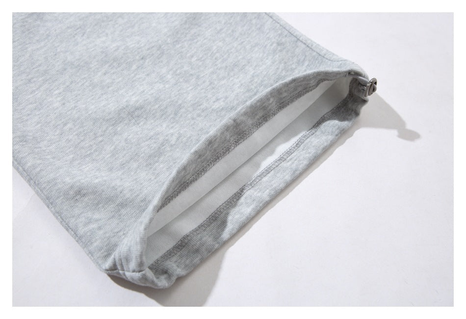 Close-up of a light gray sweatpant leg hem with an adjustable toggle.