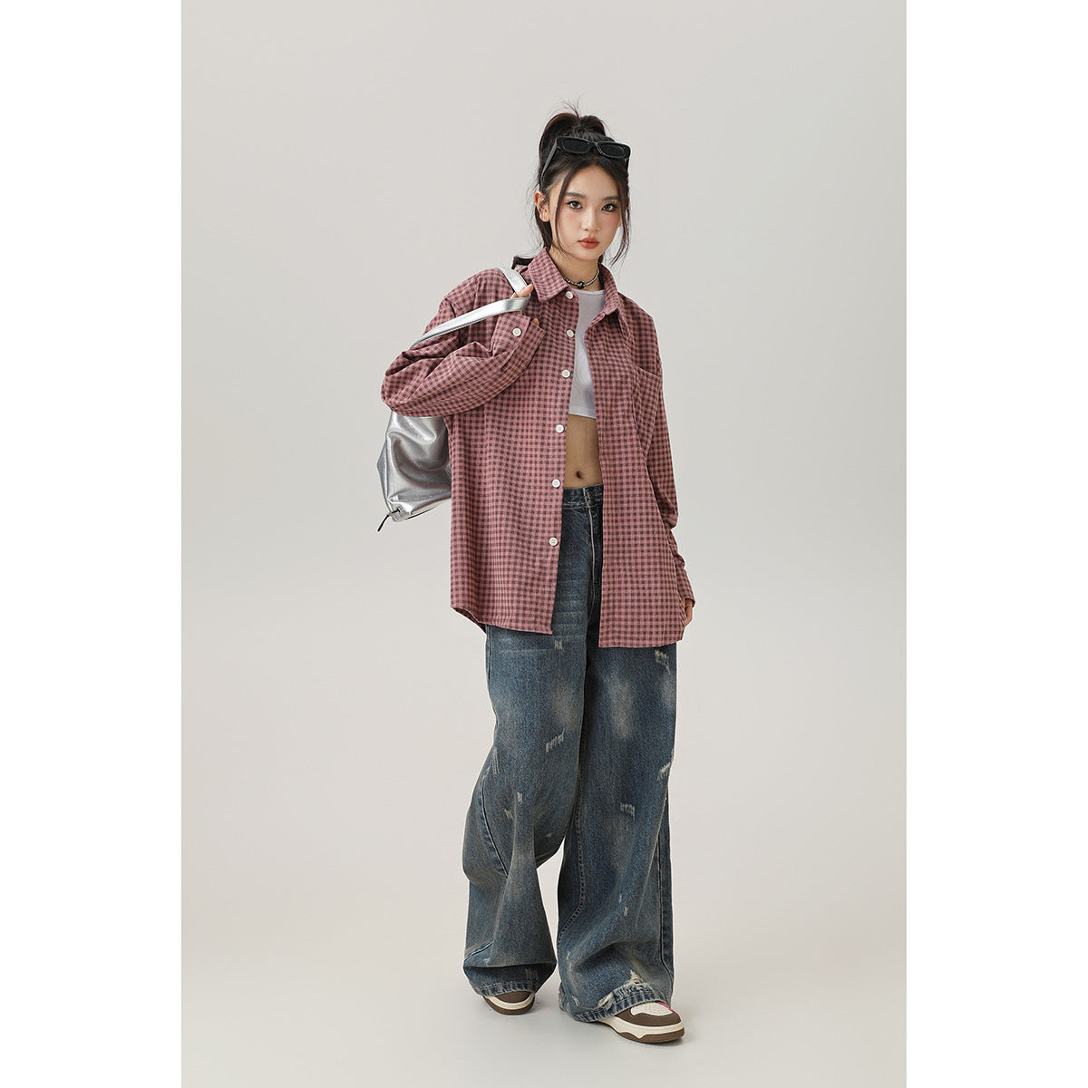 Model wearing an oversized dusty-pink check shirt with white buttons, shown from the front with loose jeans.