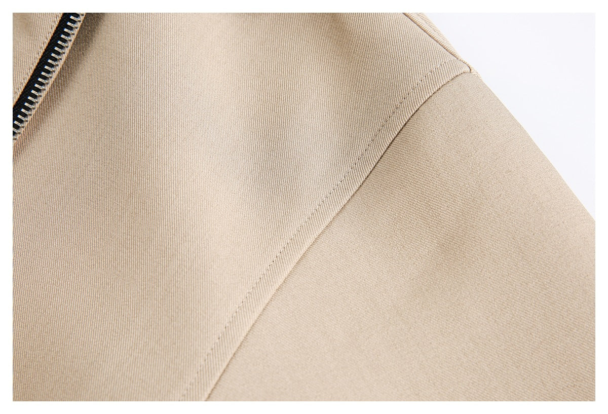 Close-up of the beige jacket shoulder seam and a section of its metal zipper.